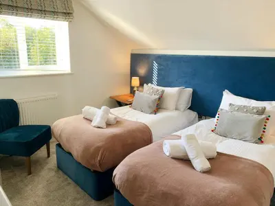 two beds in a room with a blue headboard at Waveside-Waterside with hot tubResort PoolGym in Padstow