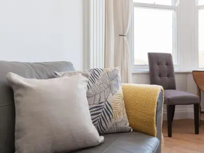 a couch with a pillow and a chair in a living room at Hepworth Apartment in St Ives
