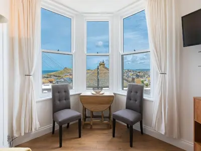 a room with two chairs and a table in front of windows at Hepworth Apartment in St Ives