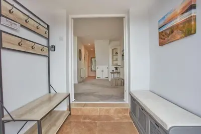 a room with a bench and a hallway with a door at Tamarisk House in Newquay