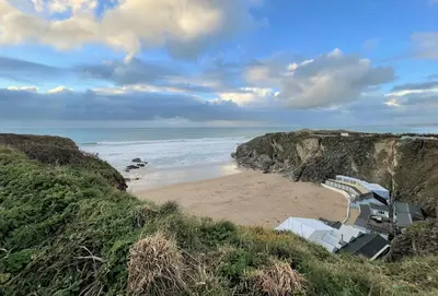 a sandy beach with chairs and the ocean at Tamarisk House in Newquay