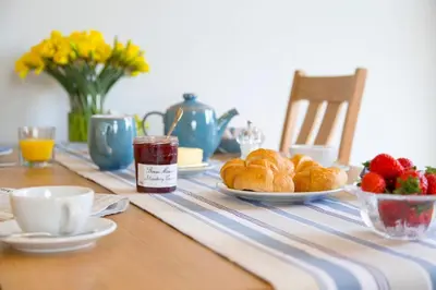 a table with a plate of croissants and strawberries on it at SandPipers Luxury hot tub lodge with 2 ensuites a private Sauna & BBQ terrace in Saint Columb Major