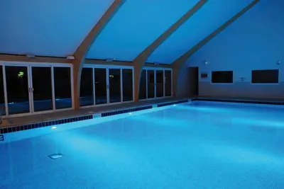 a large swimming pool with blue lighting in a building at SandPipers Luxury hot tub lodge with 2 ensuites a private Sauna & BBQ terrace in Saint Columb Major