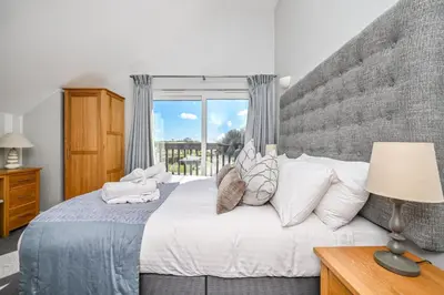 a bedroom with a large bed and a window at SandPipers Luxury hot tub lodge with 2 ensuites a private Sauna & BBQ terrace in Saint Columb Major