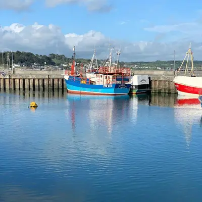 three boats are docked at a dock in the water at KingFisher Hot Tub & log Burner house on Premium lakeside with Resort Facilities in Saint Columb Major