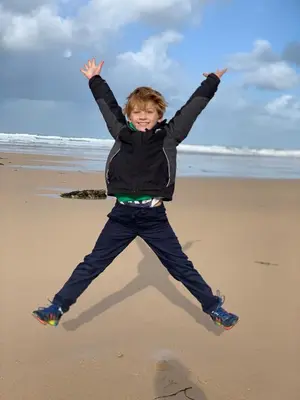 a young boy jumping in the air on the beach at Skylark sleeps 8 private Hot Tub & Dogs welcome Nr Padstow, Resort Pool Bar & Watersports in Saint Columb Major