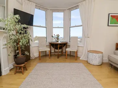 a living room with a table and chairs and windows at Whistler in St Ives