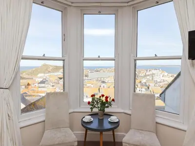 a room with three chairs and a table with flowers on it at Whistler in St Ives