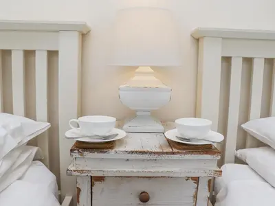 a bedside table with two cups and a lamp on it at Whistler in St Ives