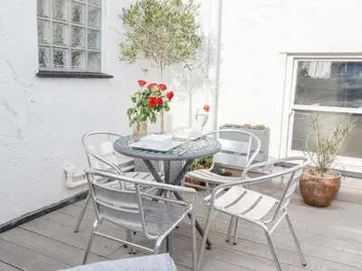 a table and chairs on a porch with flowers at Whistler in St Ives