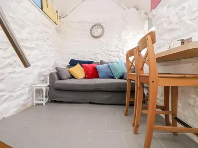 a couch with colorful pillows sitting in a room at The Old Stable in Helston