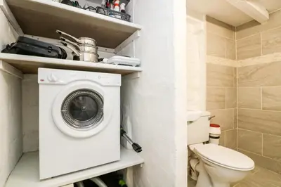a bathroom with a washing machine and a toilet at The Old Stable in Helston