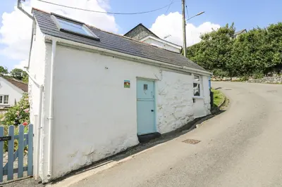 a small white building with a blue door on a road at The Old Stable in Helston