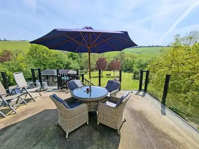 a patio with a table and chairs and an umbrella at Camellia Cottage in Saint Ewe