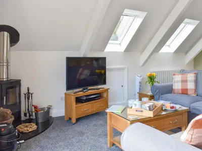 a living room with a couch and a tv at Camellia Cottage in Saint Ewe