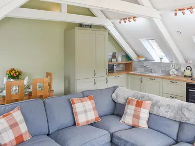a living room with a blue couch in a kitchen at Camellia Cottage in Saint Ewe