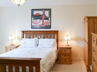 a bedroom with a large bed with two night stands at Poppy Cottage in Crantock