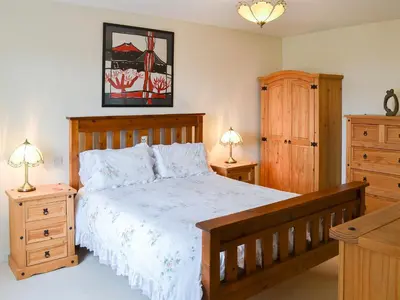 a bedroom with a wooden bed and two night stands at Poppy Cottage in Crantock