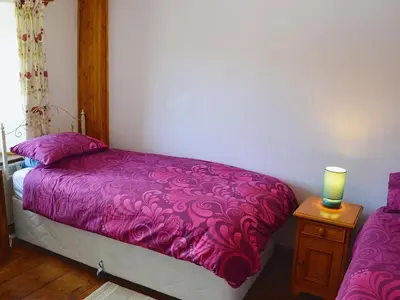 a bedroom with a purple bed and a candle on a night stand at Trecarne Cottage in Saint Cleer