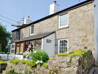an old stone house with a stone wall at Trecarne Cottage in Saint Cleer