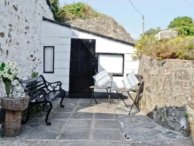 a patio with two chairs and a building at Trecarne Cottage in Saint Cleer