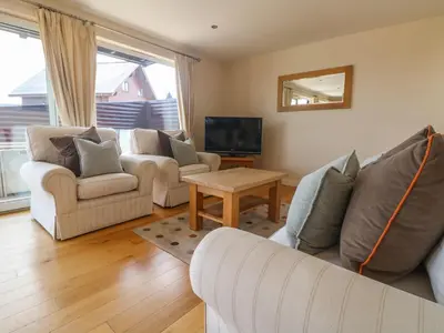 a living room with two couches and a tv at Redwood, Retallack in Newquay