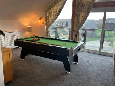 a room with a pool table in front of a window at Redwood, Retallack in Newquay