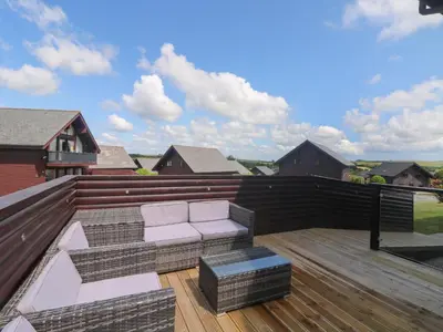a deck with a couch on a roof at Redwood, Retallack in Newquay