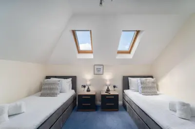 two twin beds in a room with two windows at Sea La Vie in Carbis Bay