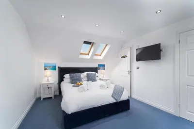 a bedroom with a white bed and a tv at Sea La Vie in Carbis Bay