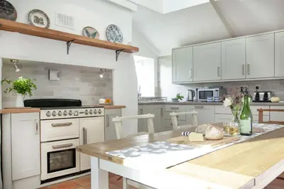 a kitchen with white cabinets and a wooden table at Laity Vean Farmhouse and Hideaway in Carbis Bay