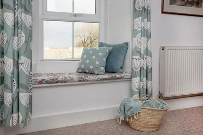 a window seat with pillows and a basket at Laity Vean Farmhouse and Hideaway in Carbis Bay