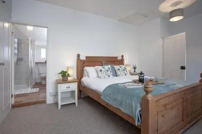 a bedroom with a large bed and a bathroom at Laity Vean Farmhouse and Hideaway in Carbis Bay