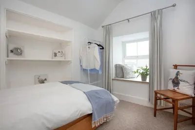 a white bedroom with a bed and a window at Laity Vean Farmhouse and Hideaway in Carbis Bay