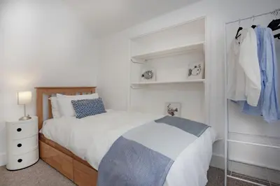 a white bedroom with a bed and a closet at Laity Vean Farmhouse and Hideaway in Carbis Bay