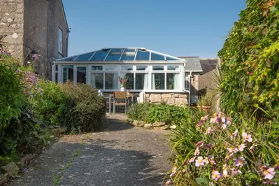 a conservatory with a glass roof in a garden at Laity Vean Farmhouse and Hideaway in Carbis Bay