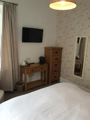 a bedroom with a bed and a dresser and a television at Portreath Arms in Portreath