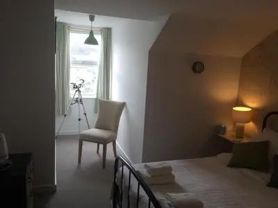 a bedroom with a bed and a chair and a camera at Portreath Arms in Portreath