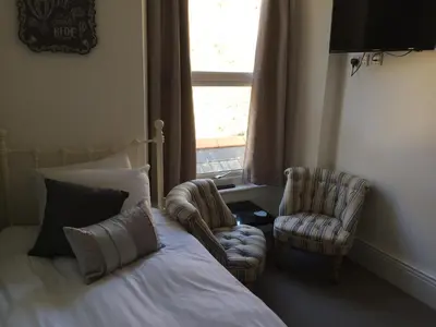 a bedroom with a bed and two chairs and a window at Portreath Arms in Portreath