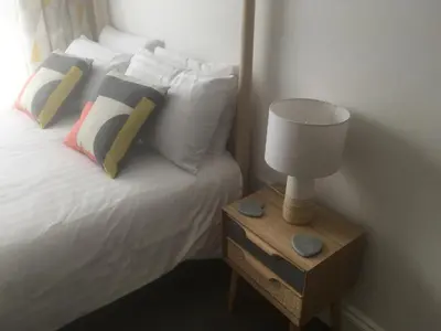 a bed with pillows and a lamp on a night stand at Portreath Arms in Portreath