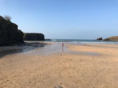 a person standing on a sandy beach near the ocean at Harbour Retreat Padstow - Entire Apartment in the beautiful old town of Padstow Harbour in Padstow