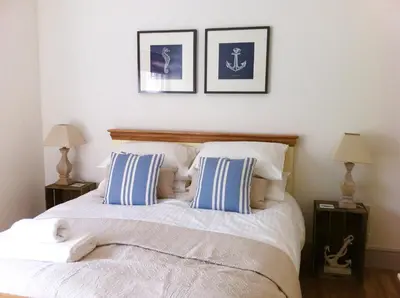 a bedroom with a bed with blue and white pillows at Harbour Retreat Padstow - Entire Apartment in the beautiful old town of Padstow Harbour in Padstow