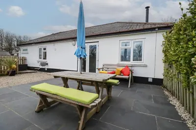 a patio with a wooden table and an umbrella at Lowenek in Bodmin
