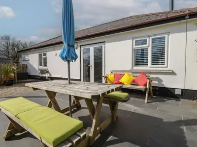 a picnic table with an umbrella and two chairs at Lowenek in Bodmin