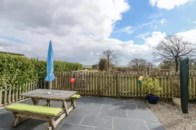 a wooden fence with a wooden table and an umbrella at Lowenek in Bodmin