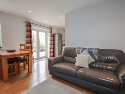 a living room with a leather couch and a table at Lowenek in Bodmin