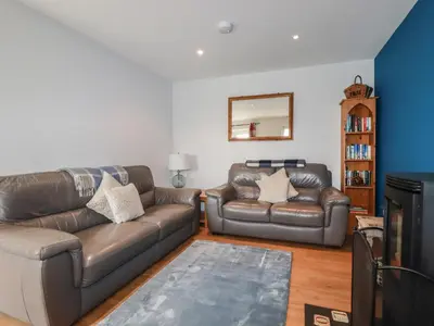 a living room with two leather couches and a mirror at Lowenek in Bodmin