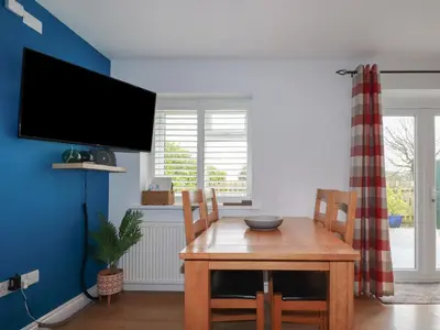 a dining room with a wooden table and a tv at Lowenek in Bodmin