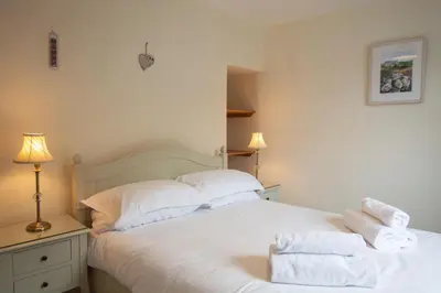 a bedroom with a white bed with towels on it at Gargoyle Cottage in St. Agnes