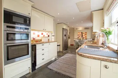 a kitchen with white cabinets and a sink at Gargoyle Cottage in St. Agnes